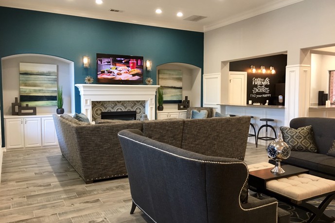 The inviting clubhouse lounge boasting comfortable seating, a cozy fireplace, and a television for entertainment, located at The Delano at North Richland Hills.