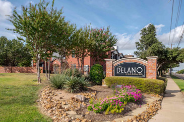 The Delano at North Richland Hills in North Richland Hills, TX  modern apartment kitchen featuring white cabinetry, stainless steel appliances, and dark wood-style flooring. 
