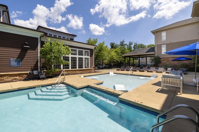 A vast pool area nestled between the clubhouse and apartment buildings at The Chelsea, offering ample space for relaxation and recreation.