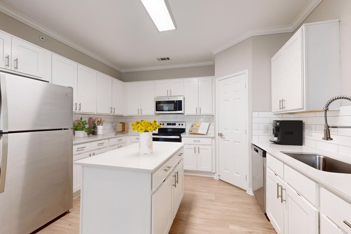 A spacious apartment kitchen featuring white cabinets and quartz countertops at The Delano at North Richland Hills.