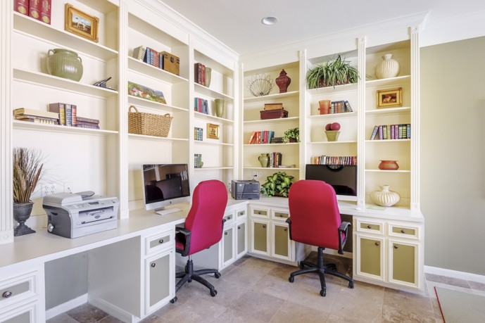 Office with two desks, two red office chairs and bookshelves, providing a productive and organized workspace.