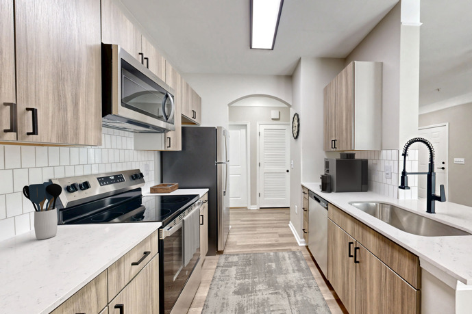 A kitchen with a sink, black refrigerator, and microwave at St James at Goose Creek.