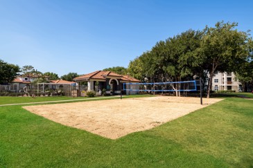 A volleyball court surrounded by foliage at The Pointe at Vista Ridge in Lewisville, TX.