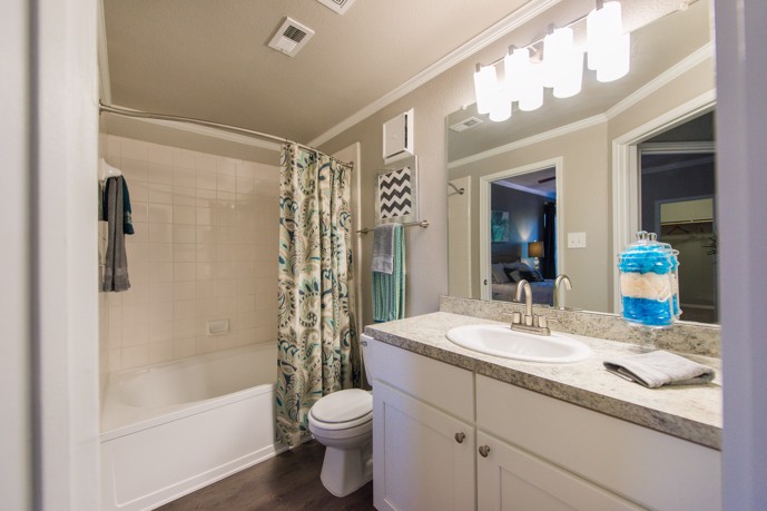 Bathroom furnished with a shower/tub combination, toilet, and sink with under-the-cabinet storage.