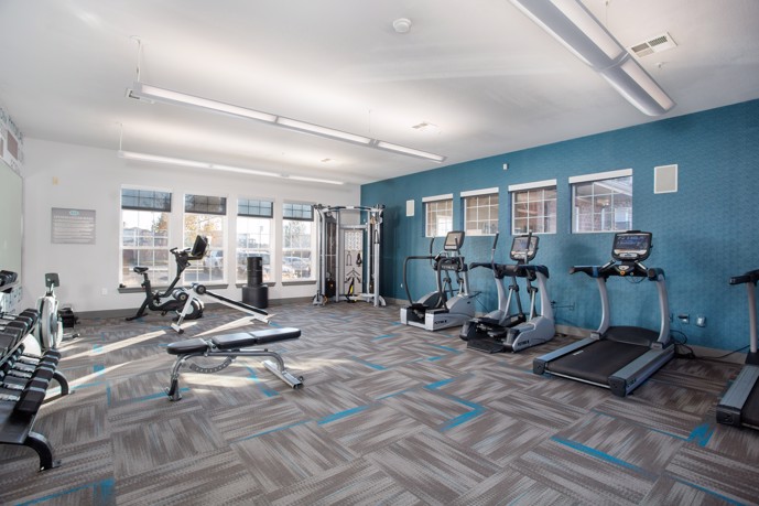 Apartment community fitness center features a weight rack, exercise bike, and treadmills