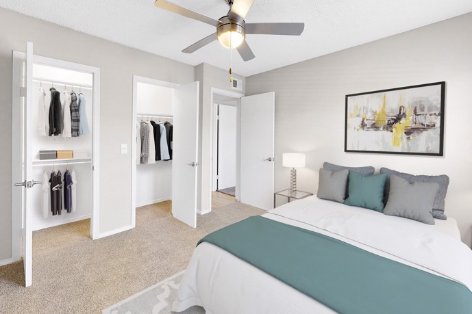 A carpeted bedroom with a ceiling fan and closet.