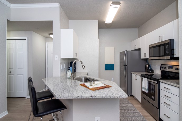 Kitchen boasting granite countertops, a breakfast bar, stainless steel appliances, and hardwood-style flooring.