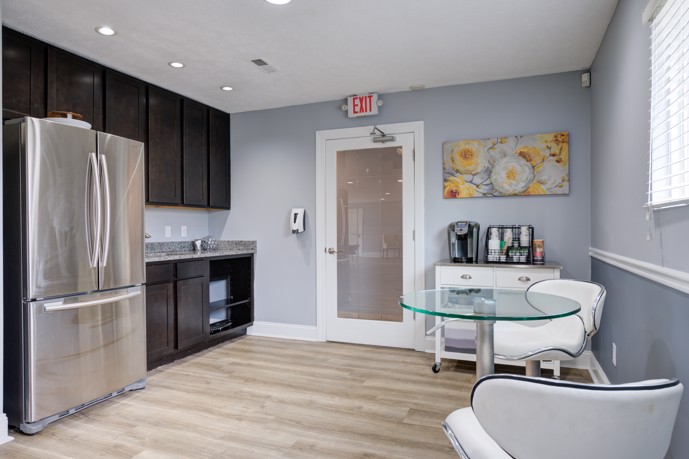 Community clubhouse kitchen with dark cabinets, stainless steel refrigerator, and a seating area