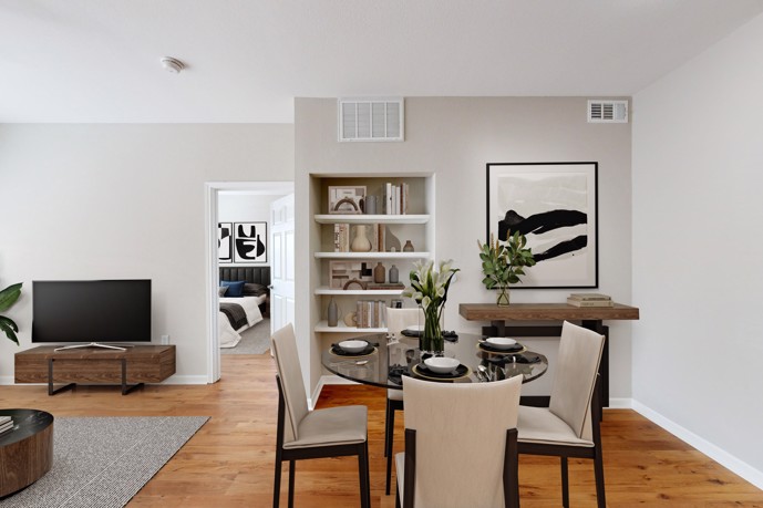 Apartment living room furnished with seating, an area rug, grey drapes, and a gas fireplace with a TV on the wall above it