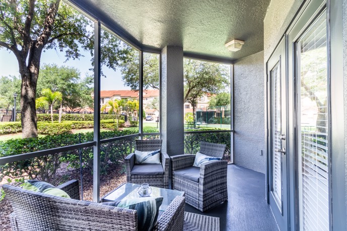 Enclosed patio featuring comfortable furniture and double doors leading to an adjacent apartment.