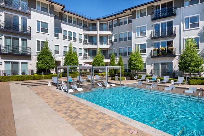 VV&M apartments' resort-style pool, complete with covered loungers, providing a perfect spot for residents to relax and soak up the sun in a luxurious and serene setting.