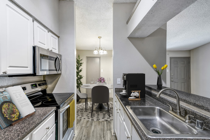 A stylish galley kitchen at Vue at Knoll Trail, featuring stainless steel appliances and elegant granite countertops.