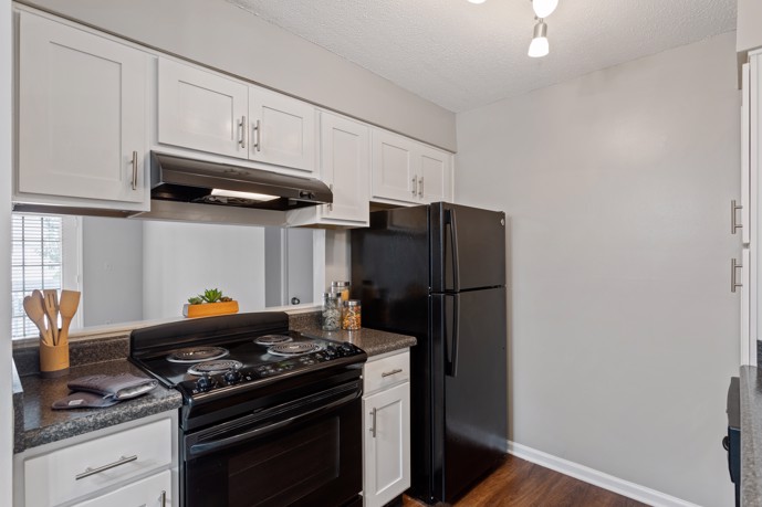 A sleek galley kitchen within Spring Hill apartments, showcasing modern black appliances, offering residents a stylish and functional space for culinary endeavors.