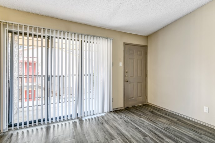 A comfortable living space with wood-style flooring and a balcony accessible through sliding doors at Vue at Knoll Trail apartments.