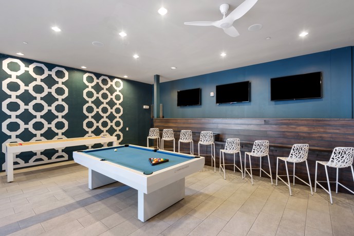 The game room at VV&M apartments' clubhouse in Dallas, Texas, featuring a pool table, shuffleboard, and comfortable seating for residents to enjoy and socialize.