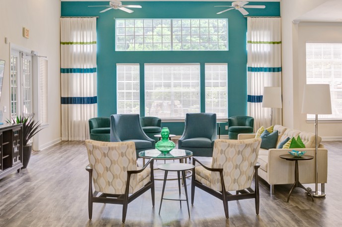 Seating area overlooking shaded windows of a turquoise and white community apartment clubhouse at Bridge Point in Huntsville, AL