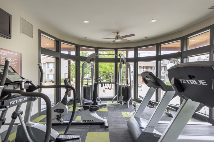 The indoor community apartment gym with treadmills and a row of windows with a courtyard view