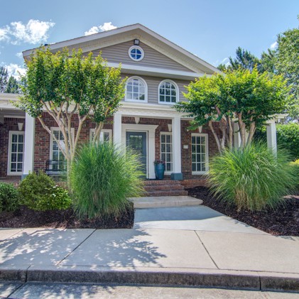 Leasing office exterior with a pathway bordered by trees and plants leading to the entrance at North Park at Eagles Landing.