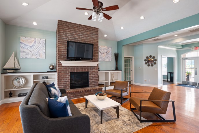 A clubhouse showcasing a cozy fireplace, ceiling fan, and comfortable seating lounge.