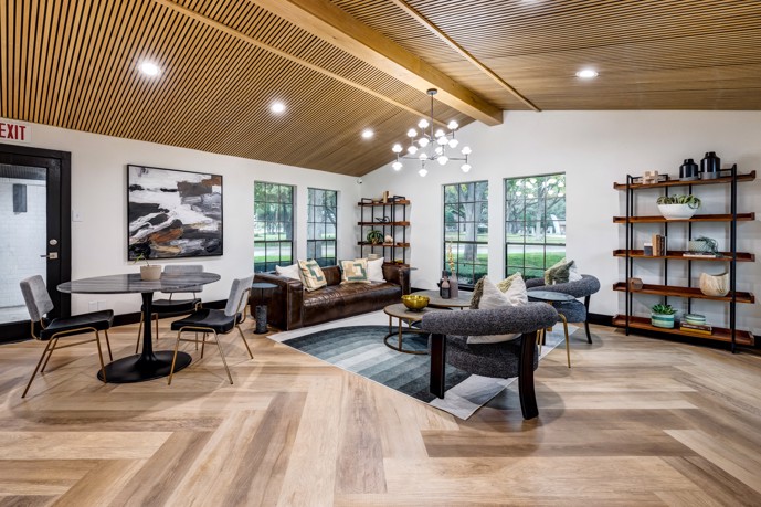 Clubhouse at Fox Trails adorned with hardwood-style flooring, a chandelier, four large windows, and comfortable seating.