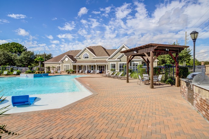 At Waterford Place at Riata Ranch in Cypress, Texas, the clubhouse features a stunning resort-style pool and comfortable loungers, creating a perfect spot for relaxation and recreation.
