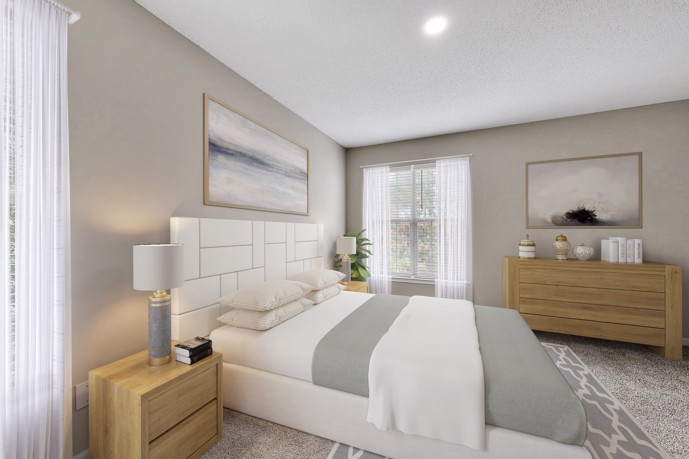 A tranquil bedroom within The Residences on McGinnis Ferry apartment, in Suwanee, GA, featuring a queen bed, soft carpeted floors, and ample natural light filtering in through the windows.