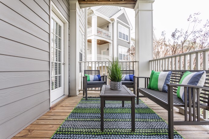 A spacious balcony at The Village at Auburn, furnished with comfortable lounge seating and a table.