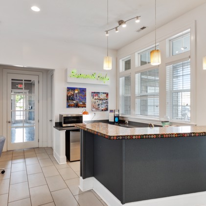 Clubhouse equipped with a community kitchen, boasting ample natural light from its large windows and adorned with tile flooring.