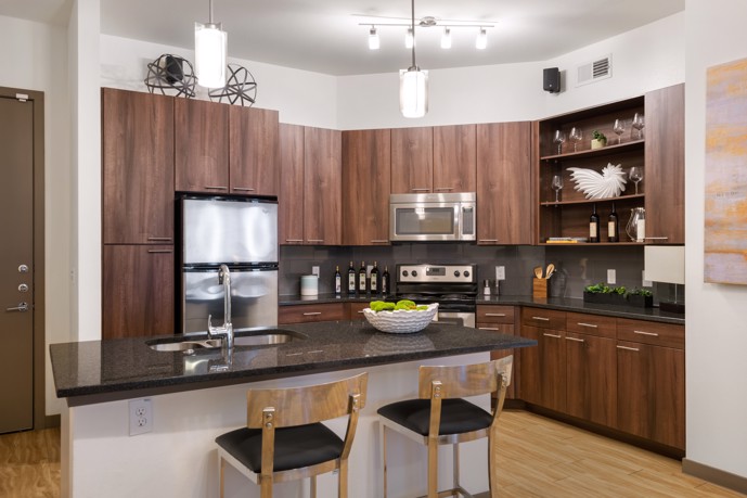 A modern apartment kitchen at VV&M apartments, featuring dark wood cabinets, stainless steel appliances, and a separate bar counter for residents to prepare meals and entertain guests in style.