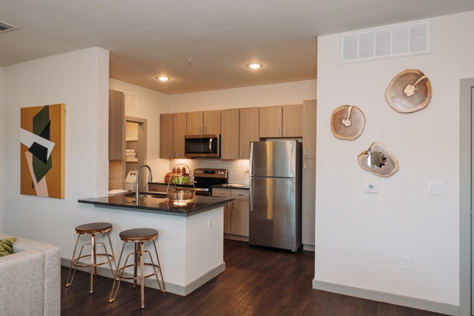 Stylish kitchen boasting modern cabinets, sleek granite countertops, a convenient breakfast bar, and stainless steel appliances.