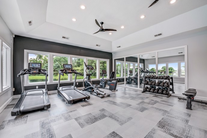 Collier Park apartment community fitness center with treadmills facing windows to the outdoors, and a rack of dumbbells along a wall of mirrors