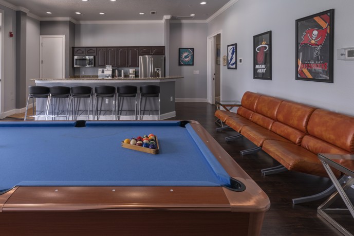 A well-appointed clubhouse featuring a large pool table, a fully stocked bar, and ample seating options, creating an inviting space for social gatherings and leisure activities at The Enclave at Tranquility Lake.