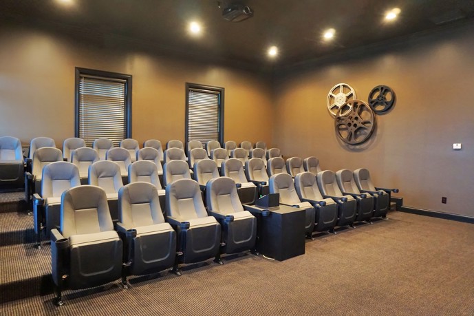 Enjoy a cinematic experience at Forty57's community movie theater, complete with tiered seating, recessed lighting, and ample natural light from two windows.