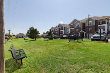 A dog run at The Shores apartments with grass and a fence for security.