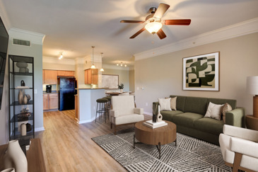 Neutral-colored furnished open floor plan apartment with the living area in the foreground and the kitchen and dining area in the background