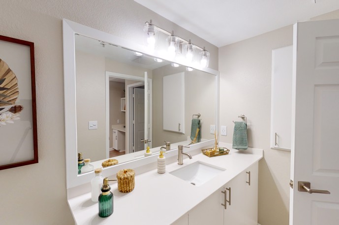 Bathroom boasting a sink, spacious countertops, and a large mirror for added convenience.