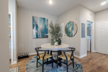 An apartment dining room with a round dining table and an adjoining kitchen at The Enclave in Tranquility Lake.