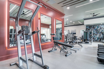 The fitness center at Waterstone at Big Creek boasts large windows that flood the space with natural light, along with a variety of gym equipment for residents' workouts.