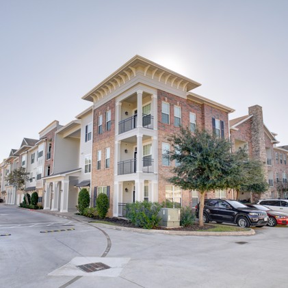 Exterior perspective of Heritage Grand at Sienna's three-story apartment building situated conveniently close to resident parking.