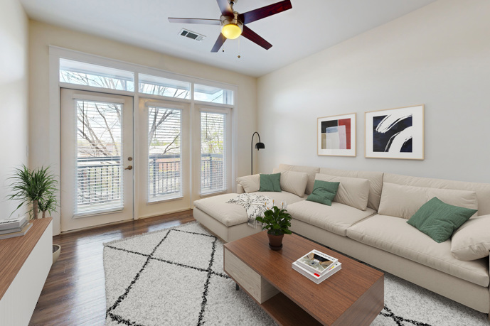A relaxing living room, featuring hardwood-style flooring and double doors leading to a balcony.
