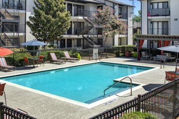 The dazzling pool with loungers surrounded by the apartments at Vue at Knoll Trail in Dallas, TX. 