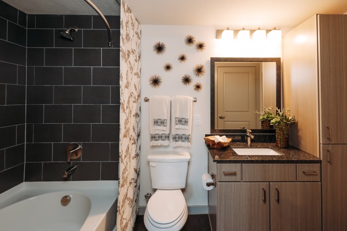Elegant bathroom featuring a tiled shower/tub combination, toilet, sink, granite countertops, and modern storage cabinets, providing both functionality and style.