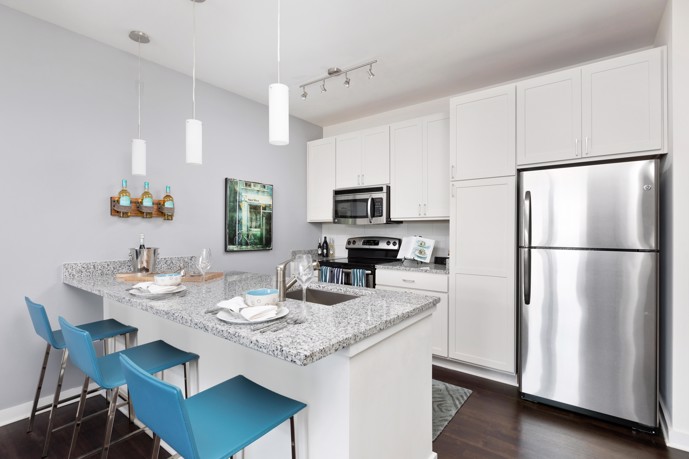 A stylish, modern kitchen, boasting an island, sleek lighting, and stainless steel appliances.