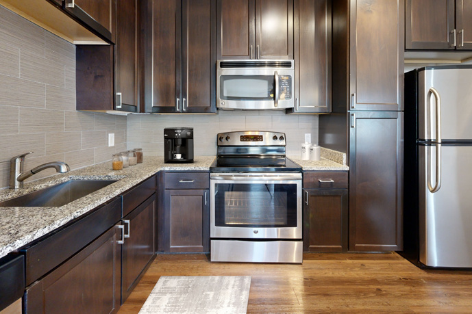 A stylish, modern kitchen, boasting an island, sleek lighting, and stainless steel appliances.