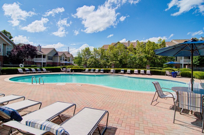 A luxurious pool area reminiscent of a resort, complete with comfortable loungers, nestled amidst the apartment buildings at Waterford Landing.