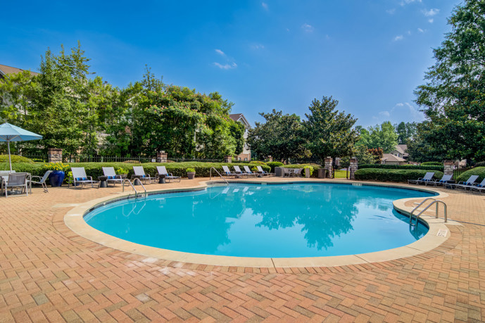 A luxurious pool area reminiscent of a resort, complete with comfortable loungers, nestled amidst the apartment buildings at Waterford Landing.