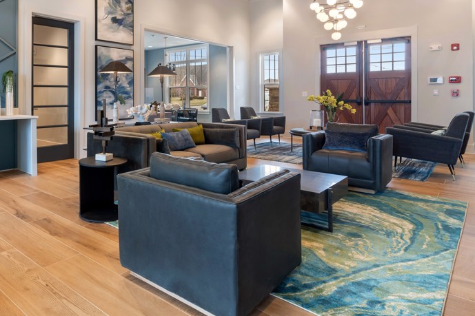 A community lounge, complete with comfortable seating, an elegant chandelier, and a welcoming double door entryway.