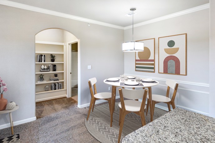 A dining room adorned with a table for shared meals and gatherings, with a hallway leading to the private bedrooms within The Shores apartments.