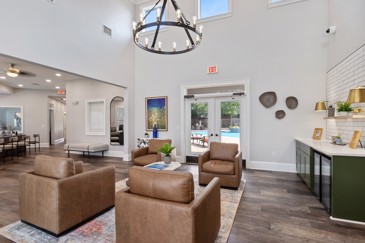 Seating area of a spacious and open community apartment clubhouse with lots of natural light and high vaulted ceilings