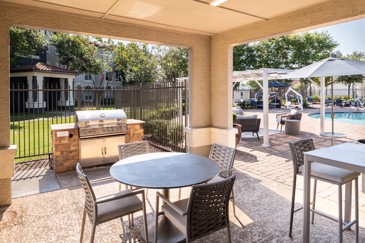 Near the sparkling pool at The Pointe at Vista Ridge, there's a covered grill area with outdoor seating, creating a perfect spot for residents to enjoy outdoor meals and gatherings in a comfortable setting.